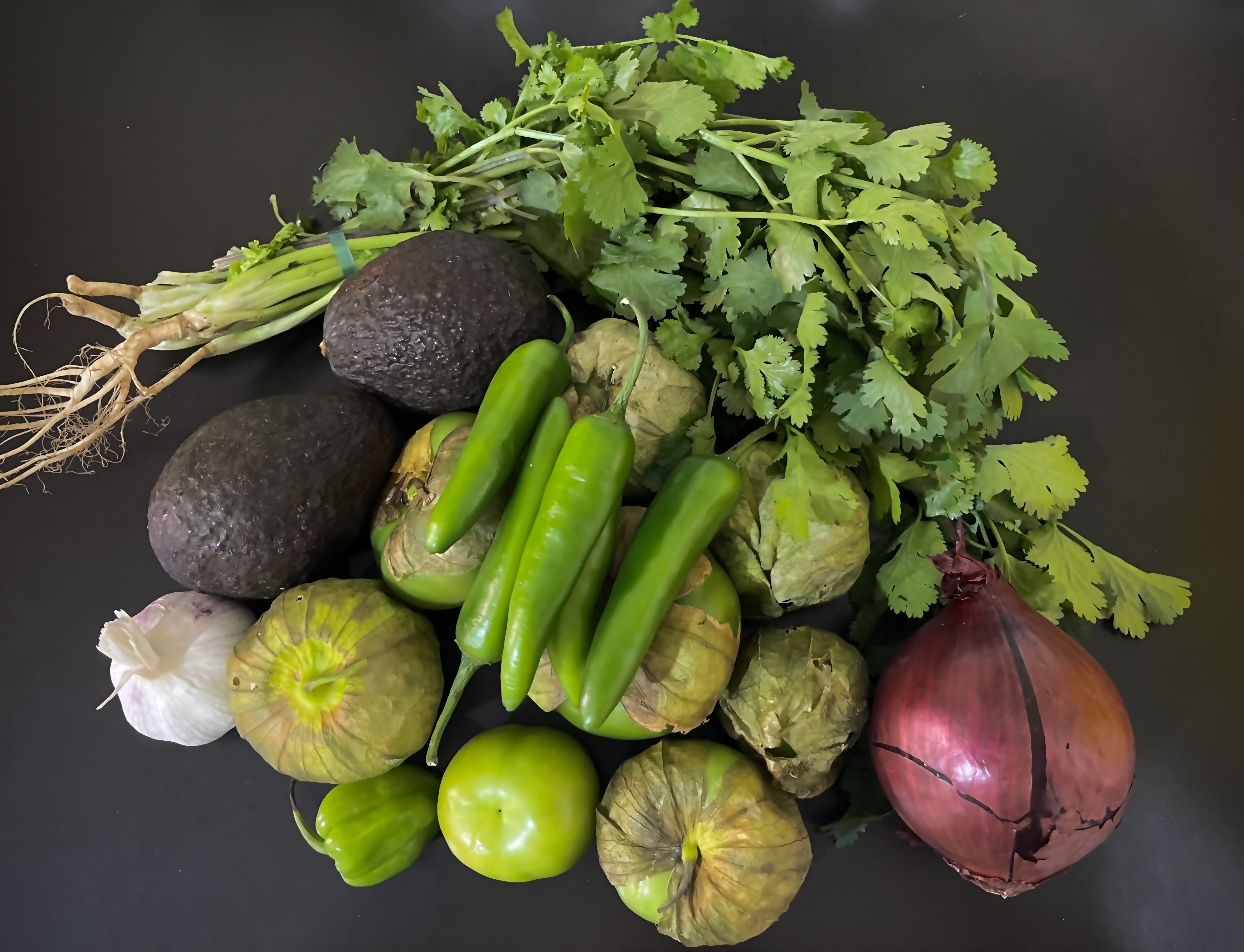 Ingredients The ingredients for making salsa verde spread out on the table. The green tomatoes are fresh still with their leaves attached!